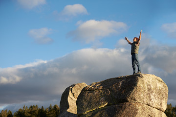 Man standing on rocky outcrop with arms raised