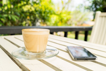 Latte art coffee cup in white mug on a table with mobile phone ,