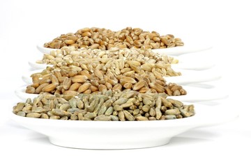 Getreidekörner (Dinkel, Hafer, Roggen, Gerste, Weizen) in Keramikschalen isoliert auf weißem...