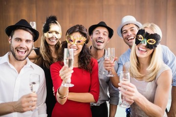 Friends holding champagne glasses laughing at camera