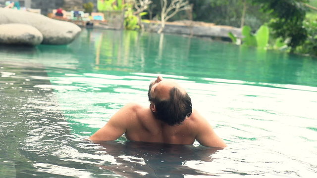 Young man relaxing in swimming pool, super slow motion 120fps
