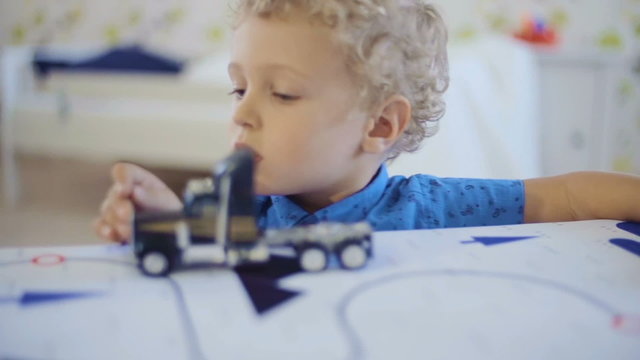 Little curly-headed boy playing with toy truck