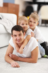 Fototapeta premium Family concept. Father with sons are playing in the room