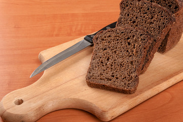 French baguette cut on wooden bread board with knife