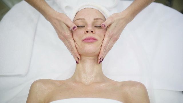 Young woman getting a facial massage at spa salon