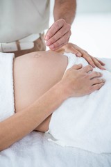 Pregnant woman in an acupuncture therapy - obrazy, fototapety, plakaty