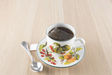 Cup of tea and teaspoon on wooden table