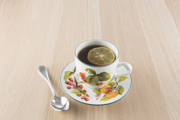 Cup of tea and teaspoon on wooden table