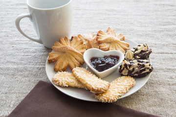 Biscotti con grani di zucchero, sfoglie al burro e biscotti cocco e cioccolato con tazza di te su...