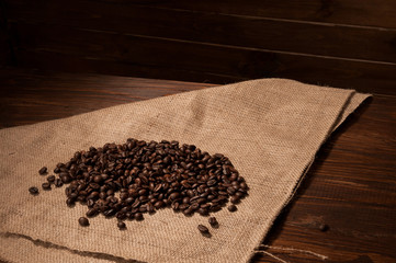 Coffee beans on sacking and wooden background