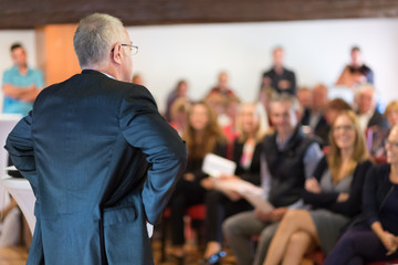 Speaker at Business Conference with Public Presentations. Audience at the conference hall. Entrepreneurship club. Rear view. Horisontal composition. Background blur.
