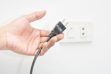 Plug on hand and socket on white wall background