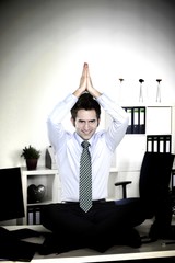 Mann im Anzug macht Yoga am Arbeitsplatz im Büro