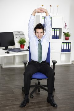 Junger Manager macht Yoga am Arbeitsplatz im Büro