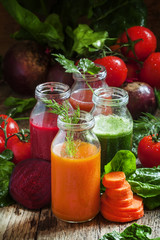 Vegetable smoothie in small bottles, dark wood background, selec
