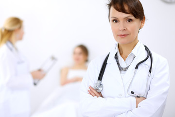 Fototapeta premium Female doctor smiling on the background with patient and his doctor