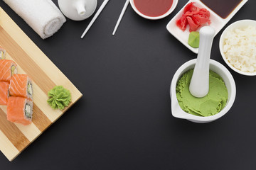 Japanese cuisine. Sushi on a wooden plate with ginger and wasabi over black background