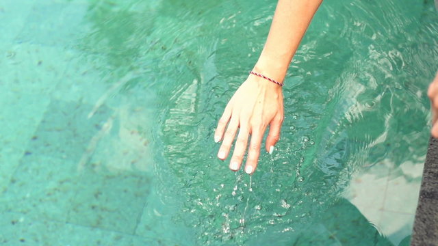 Female hand playing with water in swimming pool, super slow motion 240fps
