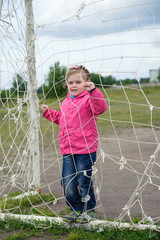girl holds hands behind a grid of football gate
