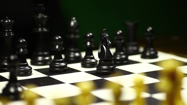 Arrangement of black chess pieces on chess board, with horse moving.