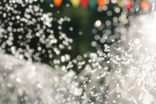 Water drops fly in the air outdoors. Blurred summertime wallpaper a lot of copyspace