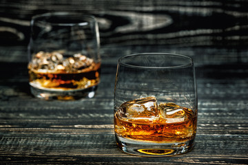 whiskey with ice on a black wooden background