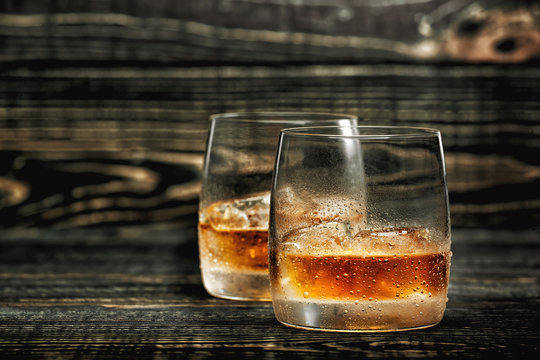 whiskey with ice on a black wooden background