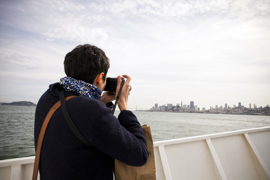 Woman taking picture of city skyline, San Francisco, California, United States