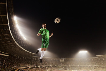Fototapeta na wymiar Athlete chesting soccer ball in stadium