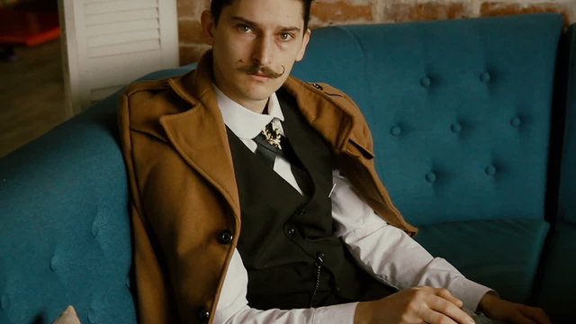 man with a mustache sitting on a sofa