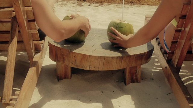 Newlyweds holding hands after drinking coconuts on the beach