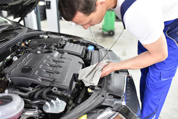 Mechaniker kontrolliert Ölstand vom Motor eines autos in der Werkstatt // professionel oil check from the engine of a car in repair shop