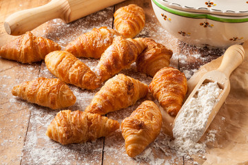 Homemade mini croissants on a wooden kitchen table.