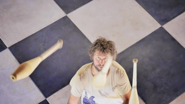 Caucasian juggler using juggling pins to practice. Slow motion