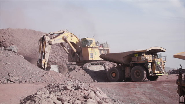 Huge Excavator, loading of copper ore on very big dump-body truck