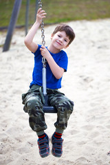 Little boy hanging on swing rope