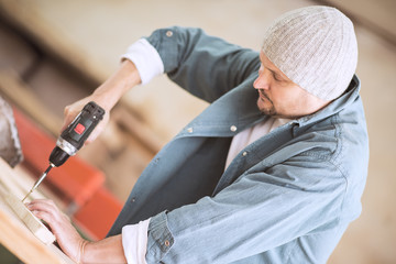 Male carpenter using drill in his workshop