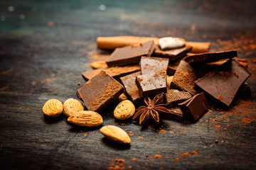 Dark chocolate with mix of nuts on rustic wooden background