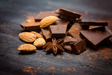 Dark chocolate with mix of nuts on rustic wooden background