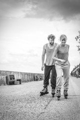 Two people race together riding rollerblades.