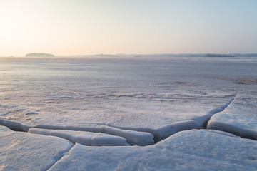 Cracked ice at a frozen lake in Finland in the morning. Copy space.