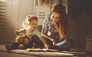 happy family mother and daughter read a book in evening