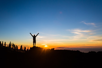 Man hiker silhouette with arms outstretched enjoy mountains