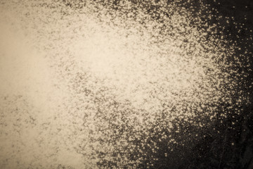 Flour spilling on black background. Toned