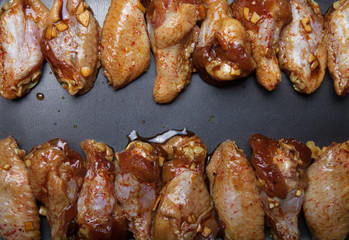 Marinated chicken wings on a black pan