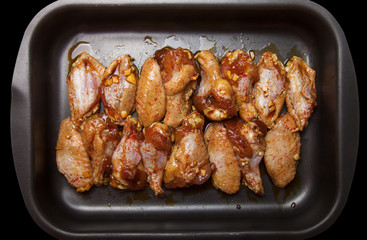 Marinated chicken wings on a black pan
