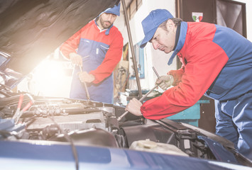 Two mechanics working on a car