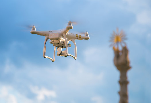 Small drone shooting a statue on blue cloudy sky