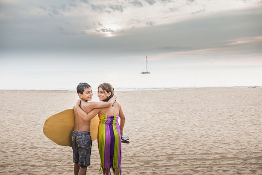Mixed race children carrying surfboard to ocean