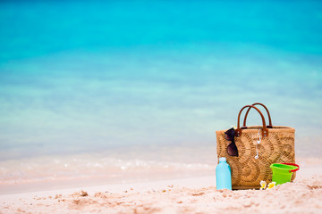 Beach accessories - straw bag, suncream bottle and red sunglasses on the beach